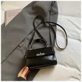 Vista superior de un mini bolso bandolera de cuero negro brillante con cierre plateado - Negro