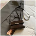 Mini bolso bandolera de piel brillante marrón oscuro colocado sobre una chaqueta gris - Marrón