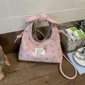 Detail van roze polkadottas met strikhandvat en zwart-wit gestreepte binnenvoering - Roze