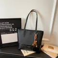 Black leather tote bag with contrast stitching, brand logo, and bohemian bead charm - Black With Pendant