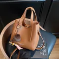 Borsa a secchiello marrone con trama litchi, ciondolo in peluche e tracolla sottile - con portachiavi / Marrone
