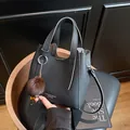 Borsa a secchiello nera in pelle a grana con ciondolo di pelliccia e tracolla - con portachiavi / Nero