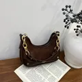 Detalle del bolso hobo marrón oscuro con cadena dorada en un libro, textura cuero - Marrón