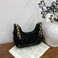 Detalle de bolso hobo de ante negro con asa de cadena dorada y herrajes vintage - Negro