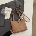 Brown lychee leather bucket bag with silver buckle and top handle in a lifestyle setting - Without Pendant / Khaki