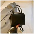 Minimalist black faux leather square handbag with dual handles and metal zipper detail - Black