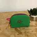Multi-layered green nylon cosmetic bag with colorful zippers and handle on wooden table - Green