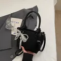 Elegante borsa a secchiello nera in pelle opaca con fiocco in pizzo e catena di perle - con portachiavi / Nero