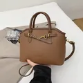 Bolso tipo concha de cuero lichi marrón con cierre dorado y correa ajustable - Marrón