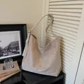 Minimalist large beige suede tote bag with shoulder strap shown in a home setting - Khaki