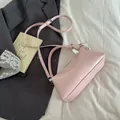 Pink textured leather shoulder bag with metallic silver ring handle on a white bed - Pink