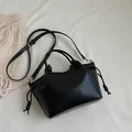 Minimalist black tote bag in faux leather with gold hardware and drawstring detail - Black