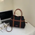 Fashionable black canvas tote bag with brown leather trim and adjustable crossbody strap - Black