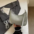 Mint green lychee texture crescent bag with detachable strap on a grey blazer backdrop - Blue