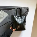 Black glossy bucket bag with silver studs and a gothic cross pendant detail - Black