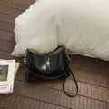 Elegante bolso de hombro en cuero negro con cierre giratorio plateado y correa fina - Negro