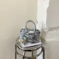 Detail der silbernen Faltenhandtasche mit süßem Plüschbär-Anhänger und Metallic-Effekt - Silber (Mit Bärenanhänger)