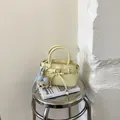 Detail einer hellgelben Mini-Handtasche mit blauer Schleife und Plüschbär-Anhänger - Gelb Mit Bärenanhänger