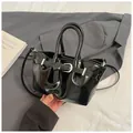Chic black glossy bucket bag with silver buckle strap and stylish crossbody handle - Black
