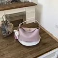 Detail of pink lychee grain leather handbag with cute plush dog charm on wooden table - With Charm / Pink