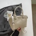 Elegante borsa a secchiello intrecciata bianca con tracolla e dettagli in argento - Bianco Sporco