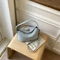 Light blue lychee pattern leather crossbody bag with silver twist lock on wooden stool - No Pendant / Blue