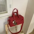 Detail of red pebbled leather bowling bag with brown horse charm on a wooden chair - With Charm / Red