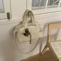 Close-up of cream tote bag with dual handles, crossbody strap and horse charm detail - With Charm / White