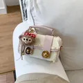 Detalle de bolso Boston con encaje, cierres dorados y colgante de oso en un sofá blanco - Rosa (Sin Colgante)