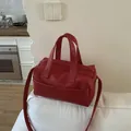 Red pebbled leather Boston bag with double handles and long shoulder strap on sofa - No Pendant / Red
