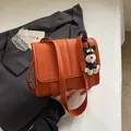 Orangefarbene Ledertasche mit Litschi-Muster und Hundeanfänger auf grauem Sakko - Mit Anhänger / Orange