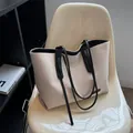 Grande borsa tote in tela beige con manici neri ed etichetta Wednesday su una sedia - Nero