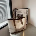 Grande borsa tote in tela crema con manici in pelle marrone su un tavolo in metallo - caffè
