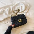 Black tweed crossbody bag with golden camellia lock and chain strap on a white blazer - Black