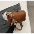 Close-up of brown Boston bag with wide woven strap and cute plush rabbit charm accessory - Brown with Pendant