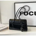 Détail d'un sac sous les aisselles en cuir noir brillant avec pendentif coeur et bandoulière - Noir