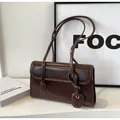 Détail du sac à bandoulière en cuir verni marron foncé brillant avec coutures et pendentif - café