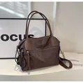 Dettaglio di una borsa tote in nylon marrone con cerniere e tracolla larga regolabile - caffè