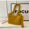 Detail of yellow quilted puffer shoulder bag featuring unique knotted strap design - Yellow