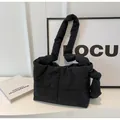 Detail view of black quilted puffer bag with large knot on the shoulder strap - Black