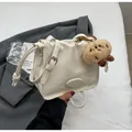 Cremeweiße Plissee-Umhängetasche aus weichem Leder mit niedlichem Plüsch-Anhänger-Detail - Gebrochenes Weiß