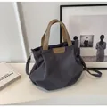 Detailed view of large canvas tote bag featuring leather patch logo and stylish handles - Gray