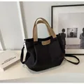 Detail of black canvas tote bag showing the leather logo patch and detachable strap - Black