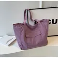 Detail of purple nylon tote bag featuring front flap pocket on a stylish white setup - Purple