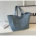 Dettaglio borsa tote in nylon azzurro con ampia tasca frontale e trama a effetto stropicciato - Blu