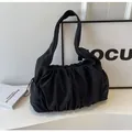 Detail of black pleated fabric texture on a stylish cloud bag with wide shoulder strap - Black