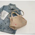 Detail of colorful embroidered letters and brand patch on khaki canvas tote bag - Khaki