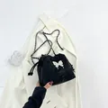 Sac seau noir tendance avec pendentif papillon blanc et bandoulière en chaîne - Noir