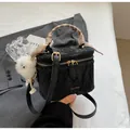 Detail of black textured bucket bag with silk scarf handle and plush pom charm - Black