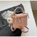 Pink mini bucket bag with silk scarf handle and plush ball charm in a stylish setting - Pink